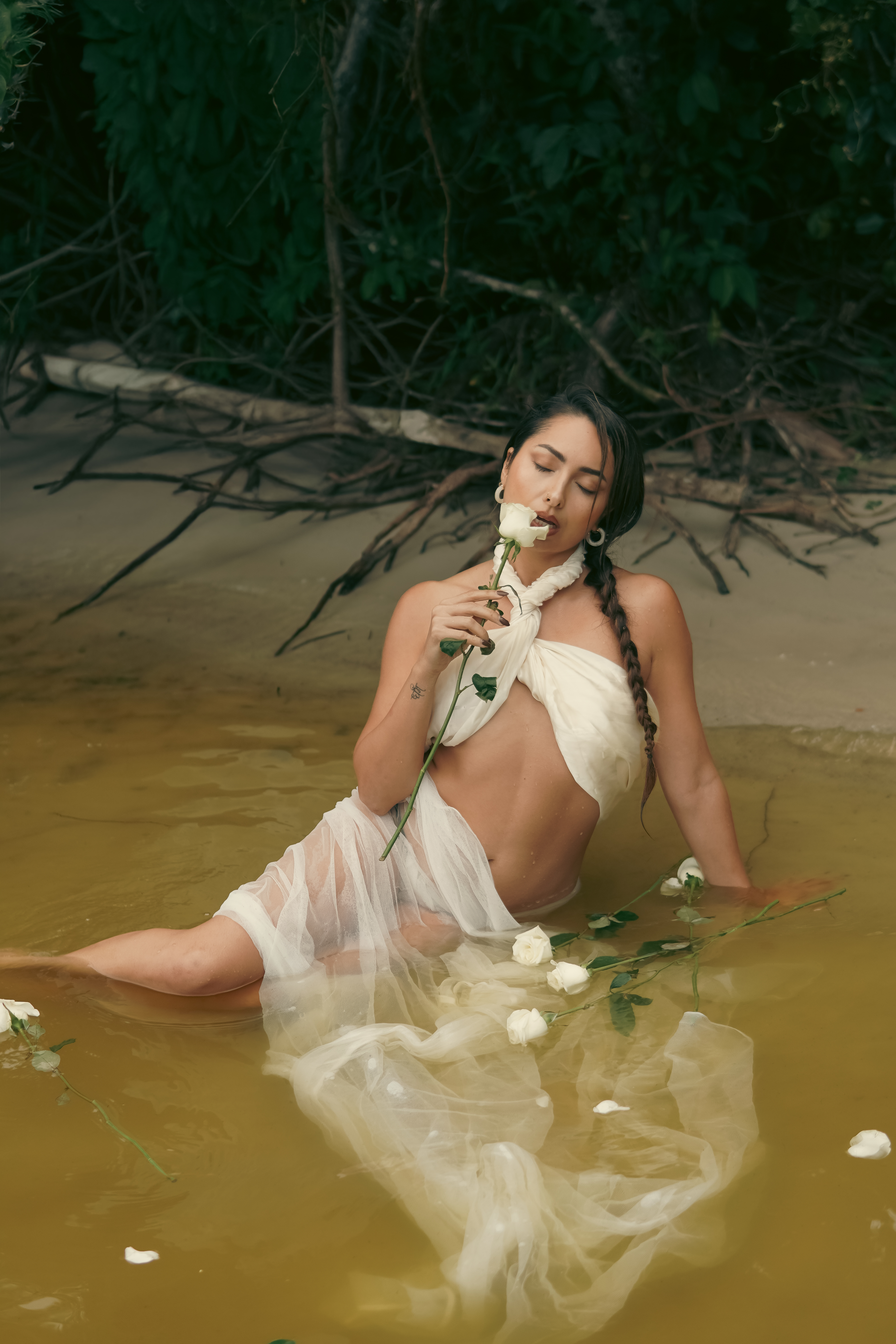 Sahara Rose reclining in shallow water with a white rose.